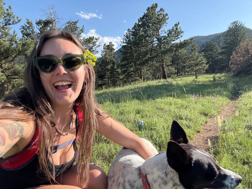 Photo of claire gormley in a mountain meadow with her dog, wearing handcrafted silver and stone jewelry