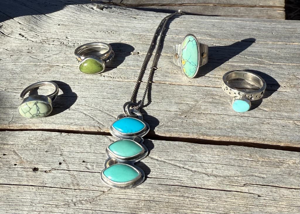 Handcrafted silver jewelry with turquoise and seafoam stones arranged on weathered wood