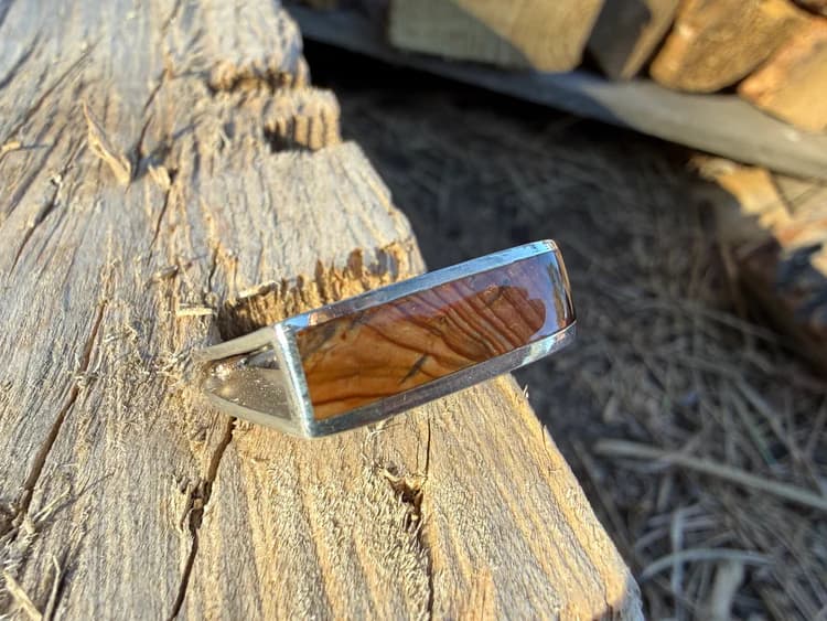 Silver ring with a rectangular jasper inlay on sunlit weathered wood