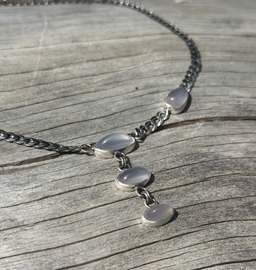Oxidized silver curb chain necklace with pale milky stones on weathered grey driftwood