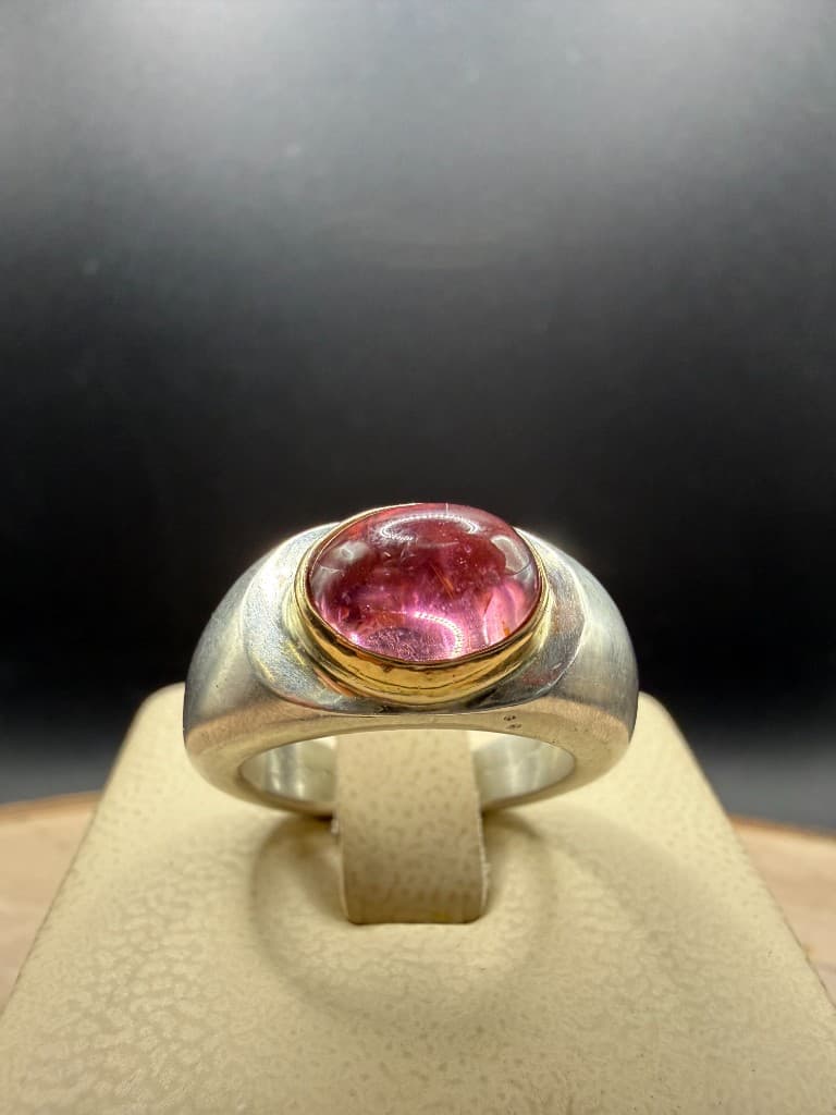 Handmade chunky silver ring with a large pink oval cabochon set in a yellow gold bezel